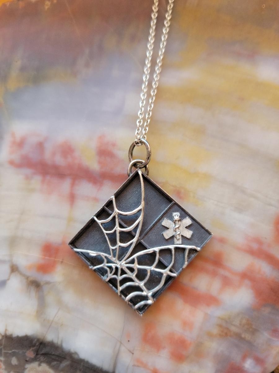 square pendant with cobweb design and medical cross
